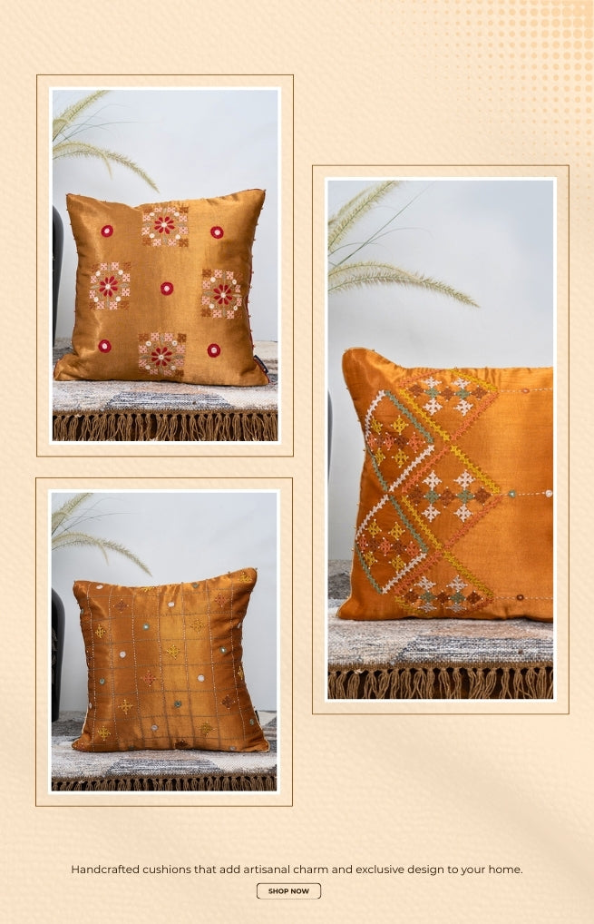 Three embroidered orange cushions with floral and geometric patterns on a beige background.
