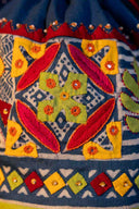 Blue triangular potli with Chandari patchwork, mirrors and brass tikki detailing.