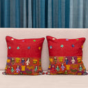 Red cushion cover featuring folk-inspired figures and houses