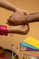 Red Karigari Dorr Rakhi – Hand-Braided Handmade Thread & Brass Rakhi